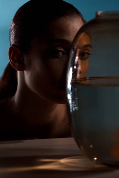 Close-up shot of a person examining their T-zone in a mirror, with visible shine indicating oily skin. The lighting is soft and diffused, highlighting the skin's texture.