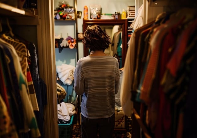 A person standing in front of an open closet, thoughtfully considering a selection of clothes that includes neutral-colored tops, a denim jacket, dark jeans, and a little black dress. The scene suggests careful planning and selection of versatile pieces.