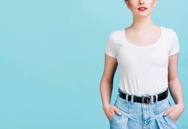 A close-up shot of a woman's torso showcasing a white t-shirt tucked into high-waisted jeans. She wears a brown leather belt with a gold buckle. Her hands are casually placed in her pockets. The focus is on the details of the t-shirt, jeans, and belt combination.