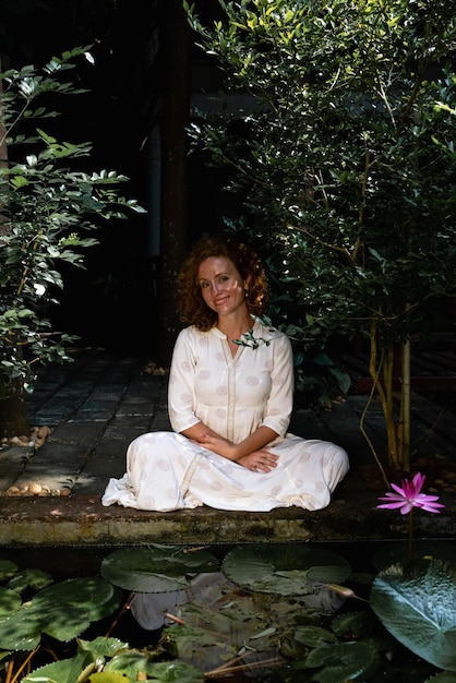 A person sitting in a relaxed pose, surrounded by lush greenery, practicing meditation, eyes closed, a peaceful expression on their face, representing mindfulness and inner calm.