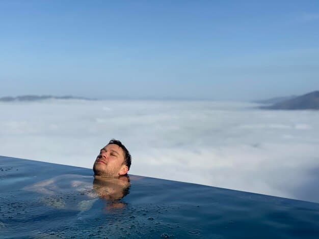 A person smiling while stepping out of a cold plunge pool in a natural setting, showcasing the invigorating and mood-boosting effects of cold water immersion.