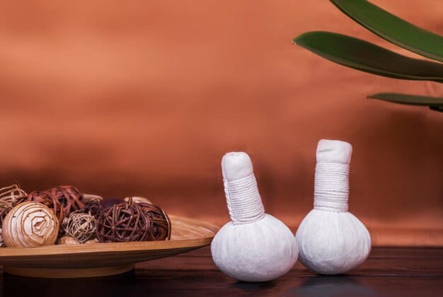 A cupping therapy set is displayed on a wooden table in a spa setting. The set includes various sizes of glass cups, a vacuum pump, and essential oils, showcasing the tools and environmenttypical for a cupping procedure.