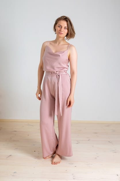 A woman wearing a monochrome beige outfit consisting of wide-leg linen pants, a silk camisole, and a lightweight trench coat. The focus is on the textures and how they create visual interest despite the single color.