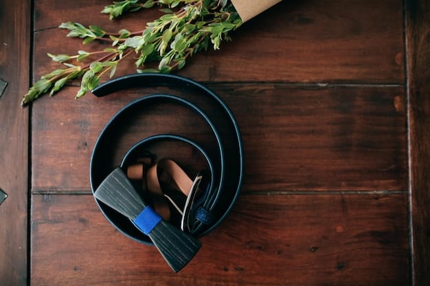 A close-up shot of different types of belts displayed on a wooden surface. Featured are a wide leather belt with a large buckle, a thin black belt with a gold clasp, and a woven belt with colorful details. The composition emphasizes the variety and textures of belts as fashion accessories.