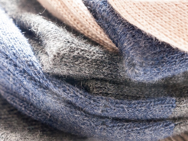 A close-up shot of different fabric textures used for layering, including merino wool, cashmere, denim, and waterproof nylon. The image highlights the importance of selecting comfortable and functional materials.