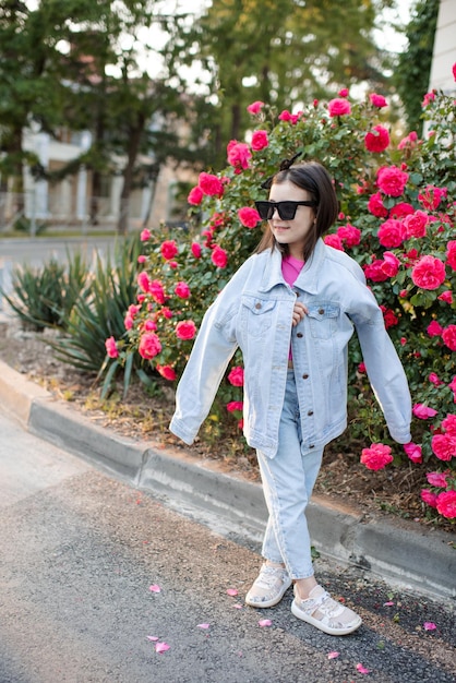 An ensemble featuring a striped top paired with floral pants and a denim jacket, accessorized with sneakers and sunglasses, capturing a stylish and relaxed casual outfit with mixed prints.