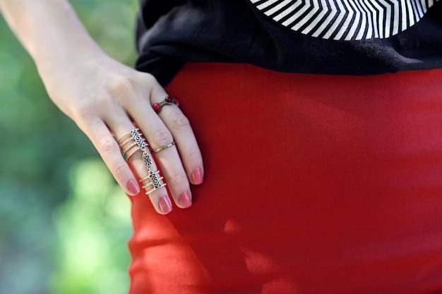 A close-up shot of a woman's hands adjusting a large, colorful statement ring. The ring is intricately designed and stands out against her neutral-toned outfit, drawing attention to her unique style.