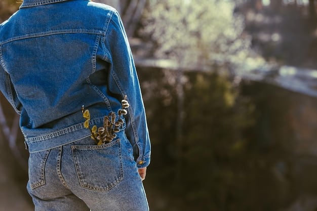 A person wearing a light wash denim shirt, a dark wash denim jacket, black jeans, and brown ankle boots, standing on a city street with a blurred background.