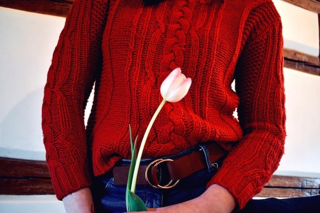 A close-up shot of a woman's outfit detail: a striped navy and white Breton top paired with a floral print midi skirt featuring red and pink roses on a dark background.
